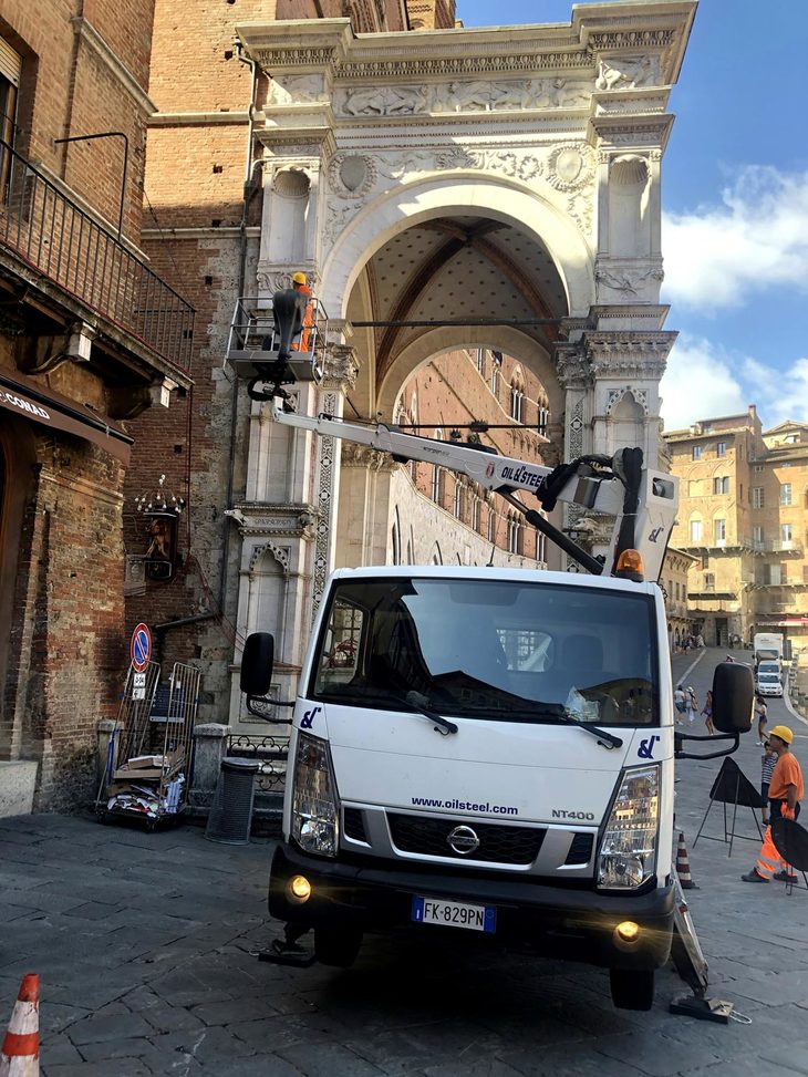 2019年夏、シエナのカンポ広場にて。シエナ市庁舎の一部を修復中の「日産NT400キャブスター」のクレーン特装車。