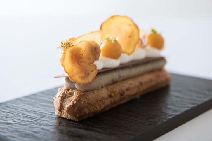 10皿目の「銀寄栗のエクレア」。じゃばらの香りをつけたクレームパティシエールを詰め、上にクリームやミルクチョコレート、さらに銀寄栗のピュレを絞って仕上げている。