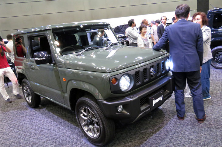 陸上自衛隊にも納品できそうな、新色の「ジャングルグリーン」が採用された「ジムニーXC」。車両の前で来場者と談笑する後ろ姿は、誰あろうスズキの鈴木俊宏社長である。
