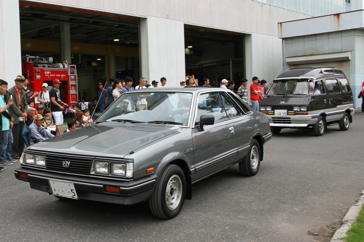 1983年「スバル・レオーネ ハードトップ4WD 1.8RX」。2代目レオーネ末期のスポーツモデルだが、4WDはまだパートタイム式だった。後ろは1993年「スバル・ドミンゴ4WD GX」。軽の「サンバー トライ」をベースにした小型7人乗りワンボックスワゴンだった初代ドミンゴの末期の高級グレードで、1.2リッター直4エンジンとフルタイム4WDを組み合わせている。
