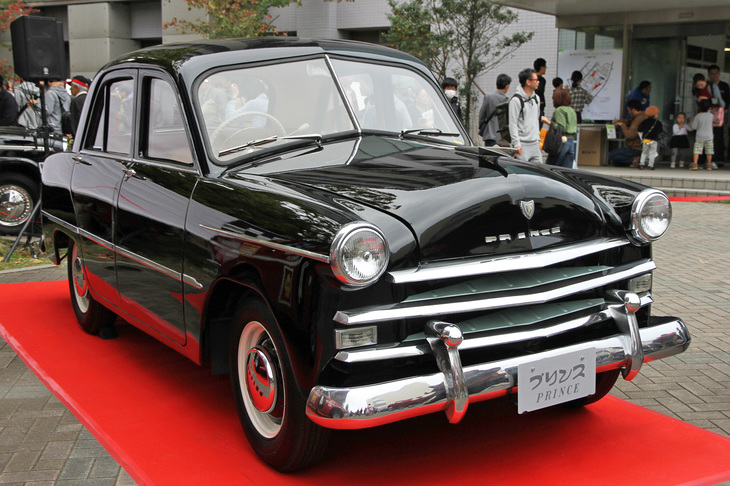特別展示車両である、日産ヘリテージコレクション所蔵の1954年「プリンス・セダン」（AISH-2型）。初代「スカイライン」の前身となるモデルで、今上天皇が皇太子時代に自らステアリングを握って愛用された個体。そもそも「プリンス」のブランドネームは、陛下が皇太子であることを公に告げる儀式である立太子礼にちなんで命名された。その後も陛下のご成婚を記念してスカイラインの上級車に「グロリア」と命名したり、国産初の御料車となるリムジン「ロイヤル」を開発するなど、プリンスは皇室と縁の深いメーカーだった。