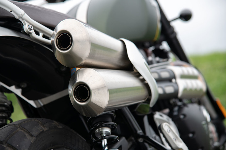 「トライアンフ・スクランブラー」シリーズの伝統ともいえるアップマフラー。カバー付きとはいえ、エンジンの横を通る排気管がライダーの足に触れるので、薄着でのライディングは禁物である。