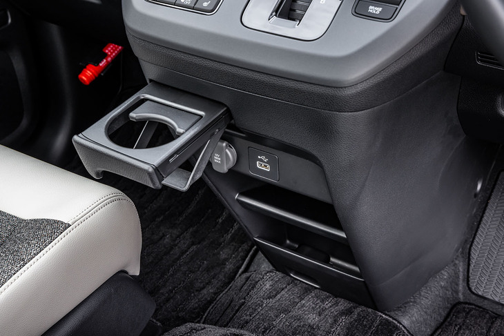 センターコンソールには、収納式ドリンクホルダーや小物用のトレー、ポケット、12V電源ソケット、USB Type-Aポートなどが並ぶ。