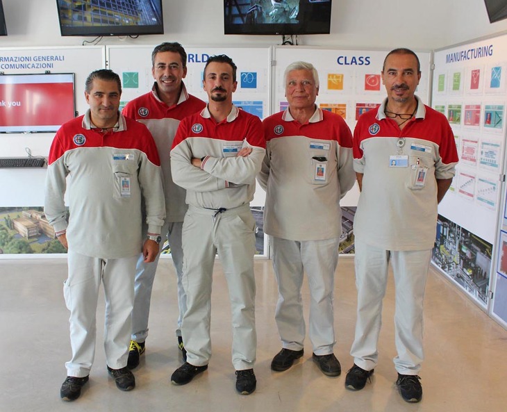 カメラを前にちょっと緊張気味の（？）工員の皆さん。つなぎはおしゃれなカラーリングで、夏場に着用するポロシャツなどは、見学者に欲しがられることもあるという。