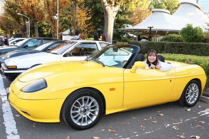 「フィアット・バルケッタ」に乗るひかりさん。同じフィアットの「500C」も所有しているそうだが、次第にMT車に乗ってみたい！ と考えるようになり、増車の候補として真っ先に思い浮かんだのが、このバルケッタだったそうだ。「MT車がいいな、できればオープン。左ハンドルならカッコいいなぁと思ったら、これがあったんです」と、うれしそうに購入の理由を教えてくれた。