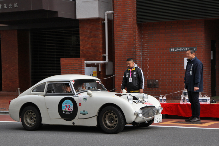 3カ所設けられたスタンプポイントのひとつである、神田川にかかる柳橋の西詰（台東区柳橋）にて。これから通過の証しであるスタンプと記念品をもらおうというのは、クーペ風のハードトップを装着した1959年「オースチン・ヒーレー・スプライトMk1」。