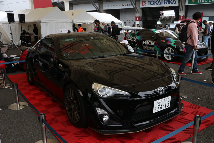 ステージ前に展示された黒の「トヨタ86」は、土屋圭市氏の愛車。ゴールドのホイールに、ボディーサイドには「BLACK LIMITED」のステッカーというモディファイは、「スプリンタートレノ」の「ブラックリミテッド」をイメージしたものだ。ちなみにナンバープレートの数字自体に意味はないが、長年愛用するAE86とおそろいにしたとのこと。