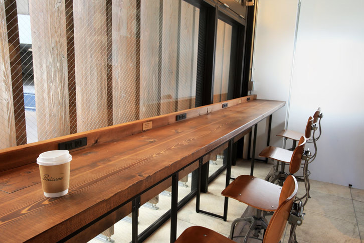木製のシックなカウンター。コンセント付きで、携帯端末の充電をしつつコーヒーを飲む人の姿も。