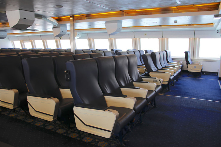 本土と島とを結ぶフェリーの船内。アームレスト収納式テーブルや機内エンターテインメント用ボタン（作動せず）からして、ひと昔前の旅客機のビジネスクラスシートを再利用していると思われる。