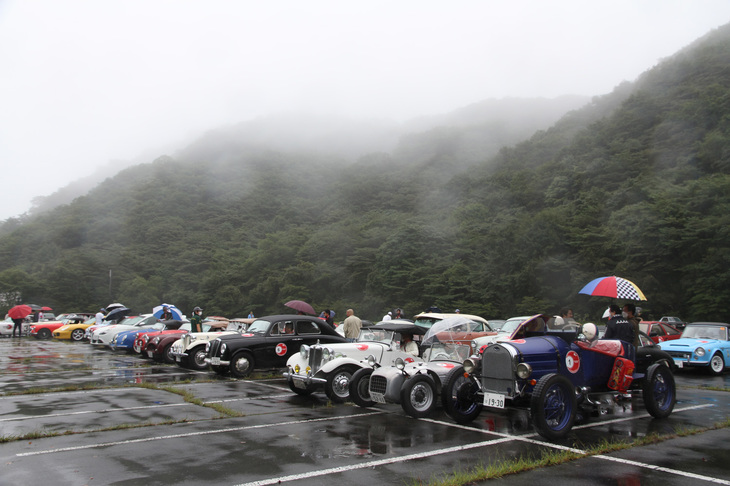 上空に霧がかかった駐車場で、2回目のPC競技のスタートを待つ参加車両。