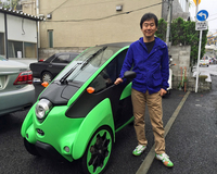 納車当日の「i-ROAD」と筆者。ボディーカラーは、希望通りグリーンを用意してもらった。駐車場は屋根なしだったがi-ROADに雨漏りはなく、充電も問題なし。