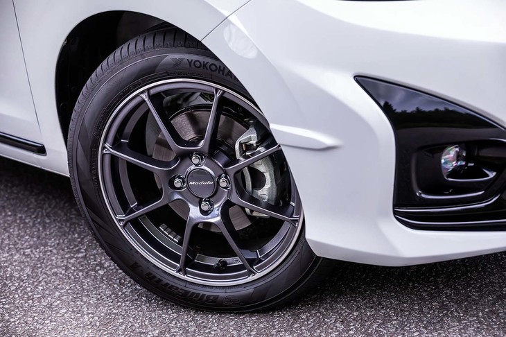 専用の16インチアルミホイール（写真）は、タイヤの接地面積を増やす目的で、あえて「適度なたわみが生じる剛性」とされている。ホイールハウス前方に設けられた「エアロフィン」は、タイヤ周辺に発生する空気の乱流を抑制することで、優れたコーナリング性能に寄与する。