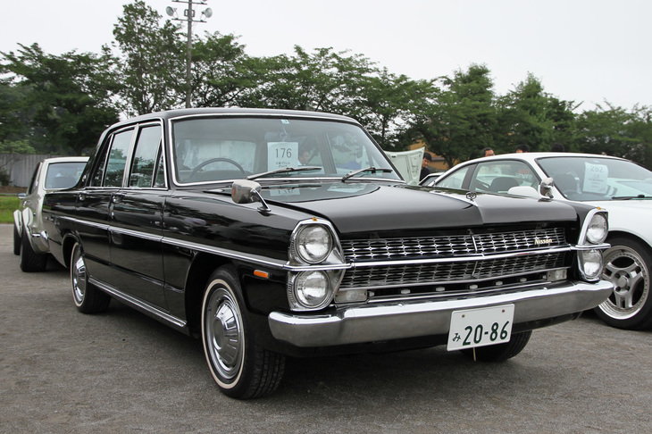 1967年「日産グロリア スーパーデラックス」。1966年の日産との合併翌年の67年にデビューした3代目グロリアのトップグレード。カタログや広告におけるメーカー表記は日産になったが、車検証上の車名にはプリンスが残されていた。凝ったフロントグリルのパターン（グレードによって異なる）に、プレミアム志向だったプリンスの意思が反映されている。