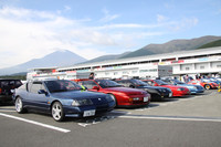 富士スピードウェイのパドックに200台以上の新旧ルノー＆アルピーヌが集結。ズラリと並んだアルピーヌ越しに雪を頂く前のアルプスならぬ富士山を望む。