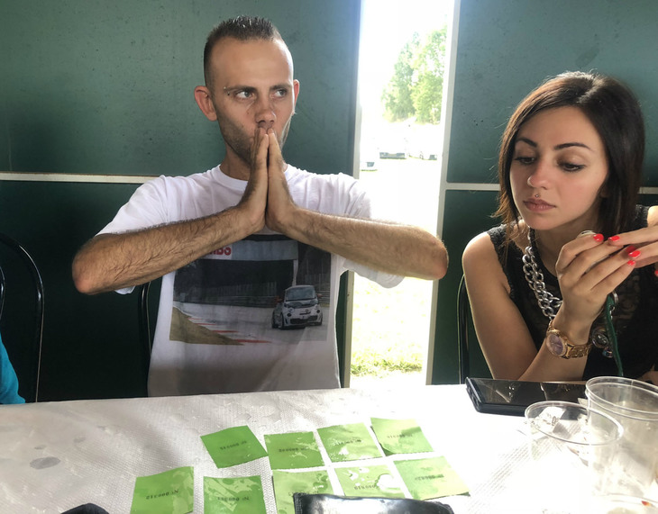 福引券を40ユーロ分も買い込んだ参加者ガブリエレ君（左）。彼女（右）がその経過を心配げに見守る。テーブルがぬれているのは、友達がふざけて水をかけたため。愛車をプリントしたTシャツに並々ならぬパッションを感じる。