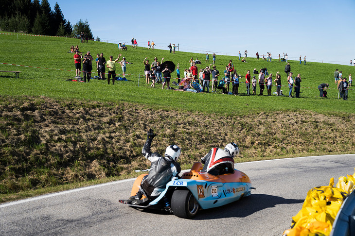山を下るマシンを待って手を振る観客たち。それに応え、ライダーも手を振り返す。