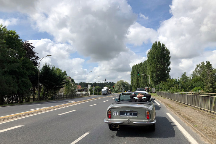 信号待ちの列に並ぶ「DB6ヴォランテ」と、退屈そうに頭に手を当てるドライバー。