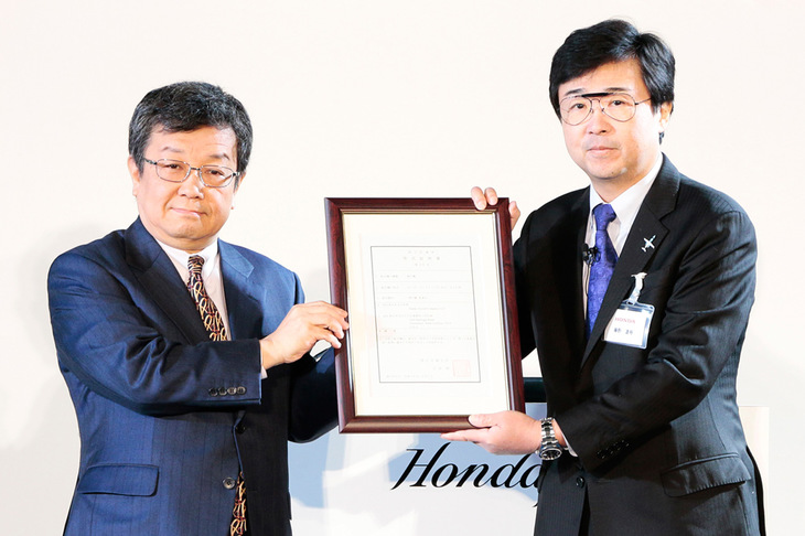 型式証明書とともに撮影に応じる、国土交通省の蝦名邦晴航空局長（左）とホンダ エアクラフト カンパニーの藤野社長（右）。