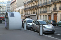 写真で路肩に止まっているクルマが、オートリブに使われる「ボロレ・ブルーカー」。歩道に見える半円形の構造物は、中で利用登録などを行う「エスパスオートリブ」。