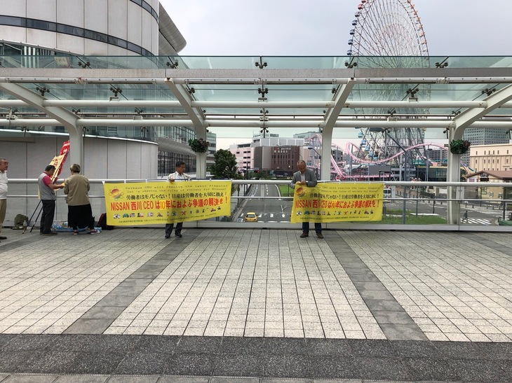 会場近くで見かけた日産に争議解決を訴える人々。横断幕の「10」の部分だけ色が違うところに、争いの歴史を感じる。