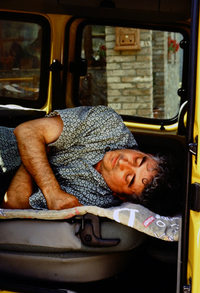 「出張イラスト・パフォーマンスのときはたびたび、このようにして車中泊する」と実演するヴァレンティ氏。2003年。