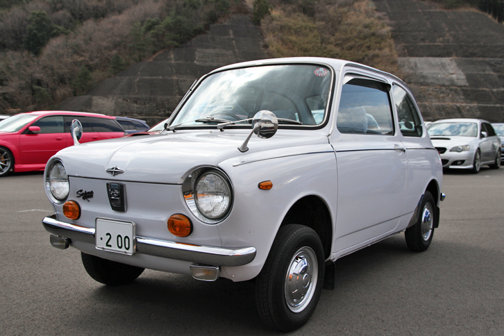来場者のパーキングスペースより、1970年「スバルR-2デラックス」。「スバル360」の後継モデルとして69年に登場したR-2（リアエンジンの2代目という意味）の、オリジナルな状態が保たれた初期型。