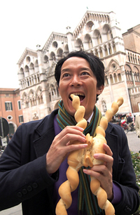 エステンセ城とともにフェラーラの象徴であるサンジョルジョ大聖堂をバックに。念願の“ランボが愛したパン”を食べる筆者。