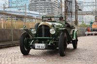 汐留西公園の裏手にあるJRの線路沿いの道を行く、これも今回の注目モデルである1927年「ベントレー4-1/2リッター オールド・マザー・ガン」。1928年のルマン24時間で優勝したマシンで、日本を代表するロールス・ロイス／ベントレーのエキスパートであるオーナーの涌井清春さんがドライブ。