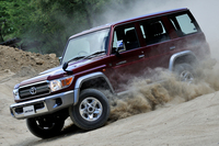 砂塵（さじん）を巻き上げて走る「70系」。副変速機付きのパートタイム4WDに、前輪のデュアルモードオートマチックロッキングハブ、オプションで用意される電動デフロックなど、走破性を高めるための機能や装備は充実している。