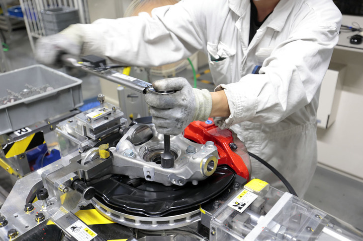 フロントサスペンションの工程はご覧のとおりの手作業。2人の熟練工によって入念に、しかし一台分を7分という早いタクトタイムで組み立てる。