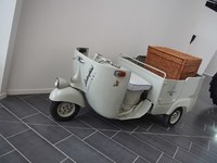 「ピアッジョ・アペ」。籐（とう）製の籠が載せられて展示されているが、後部はミニタクシー仕様である。