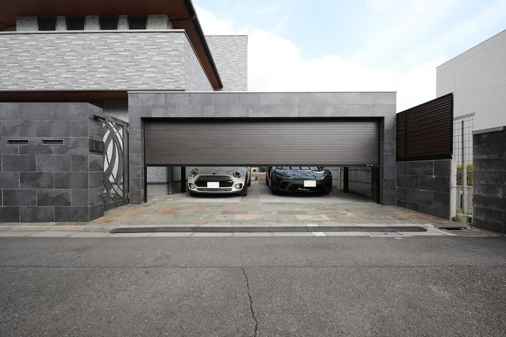 フラットデザインのスチール製ガレージシャッター「ポルティエ」の施工例。建物にマッチしたチャコールネズコのシャッターの内側にはミニとマクラーレンGTが収められている。