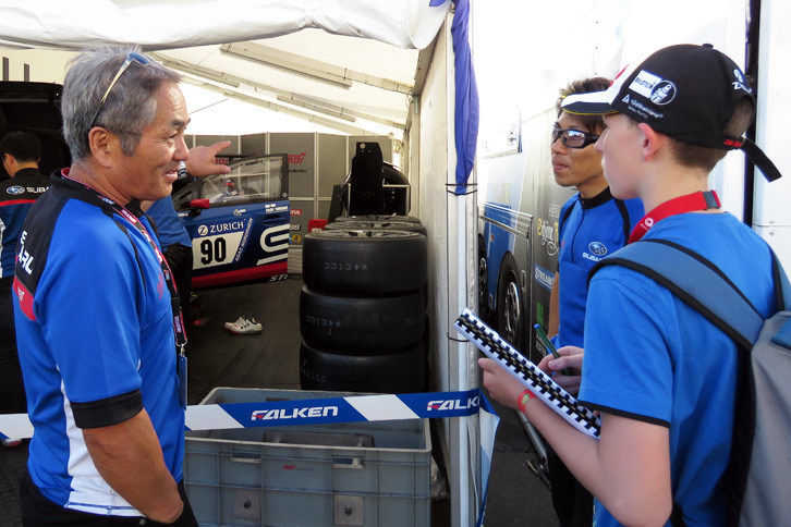 決勝前日のパドックにて、テントを訪れたスバルファンの少年（右手前）に対応する辰己英治テクニカルアドバイザー（左）。「ドライバーに会える機会はある？」とたずねられたそうだ。