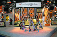 【写真上】いつもはプロ野球の熱戦が繰り広げられる福岡ドームが、この日はクルマ好きの祭典に。ふだんは広く感じるグラウンドもこの日はいくつものブースが所狭しと並んでいた。【写真下】東京、大阪と続いてここ福岡でも「モバHO」は積極的に展開。元気のいいアクションステージが見る者の足を止めていた。