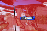 テールゲートやフェンダーパネルに装着される「HYBRID」のバッジ。色は、既存のマイルドハイブリッド車は白、新設定のフルハイブリッド車は黒となる。