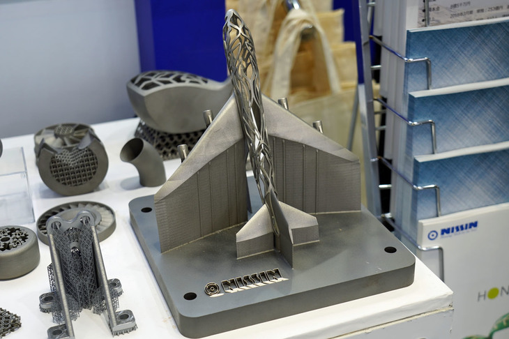 日進製作所の金属3Dプリンターで作れるのはフットプリント800mm×800mmのサイズまで。プレートの上に20μ～30μ（μは1000分の1mm）のアルミパウダーをまき、それをレーザーで焼き固めていく。製作には、写真の航空機のミニチュアで3～4日ほどを要すという。