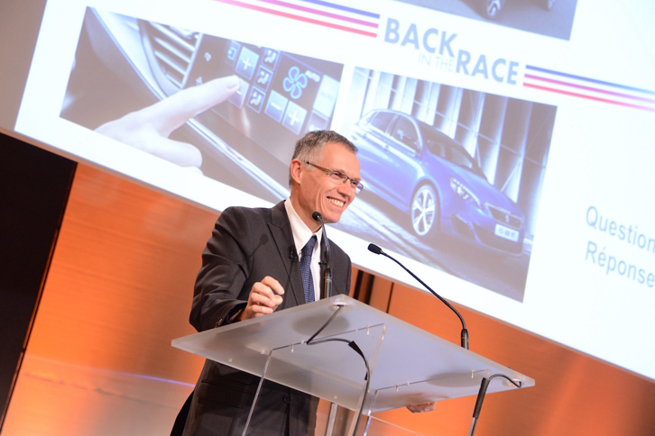 経営改革のスローガン「バック・イン・ザ・レース」のスライドを前にスピーチするPSAプジョー・シトロエンのカルロス・タバレスCEO。