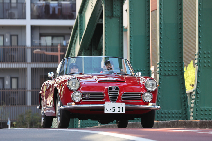 柳橋を渡る1967年「アルファ・ロメオ2600スパイダー」。トゥーリングデザインの4座コンバーチブルボディーに2.6リッター直6 DOHCエンジンを積む。