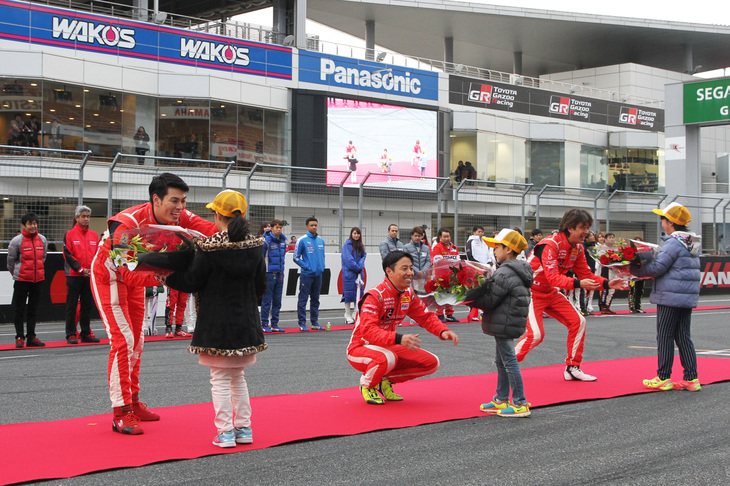 ホームストレート上に出場全ドライバー、監督、ニスモアンバサダーとレースクイーン、そして出走マシンがそろったフィナーレにおける表彰シーン。今季のスーパー耐久 ST-Xクラスで「Y's distraction GTNET GT-R」を駆ってシリーズチャンピオンを獲得した藤波清斗、星野一樹、浜野彰彦（左から）が、サーキットのお仕事体験に参加したキッズから花束を贈られた。