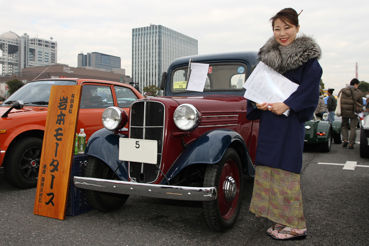 クルマに合わせたコスプレ姿（？）のご婦人が寄り添う、陸運支局がなかった時代の“5”で始まる東京ナンバーを付けた1937年「ダットサン16型セダン」。オーナーはジープに強いショップである岩本モータース。同社の代表が板金職人の高齢化に伴う減少に危機感を覚え、“鈑金（ばんきん）寺子屋”の設立を企画。その資金捻出のために、このダットサンを手放すことにしたという。