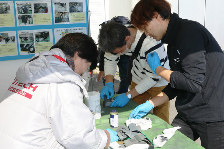 日産モータースポーツ＆カスタマイズのエンジニアによる、さまざまな体験型コンテンツも人気。写真はメダル型キーホルダーづくりのコーナーで、紙やすりと研磨剤で金属に美しい輝きを与える工程を体験できた。これ以外にも、形状の違うミニカーにより、空力の違いが生む走りの差を学ぶコーナーなど、子供から大人まで楽しめる、奥深いコンテンツが多数用意されていた。