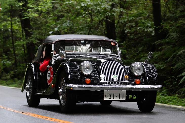 スタンプポイントを出て再びワインディングロードに向かう、木々の緑が映り込んだボディーが美しい1974年「モーガン4/4」。