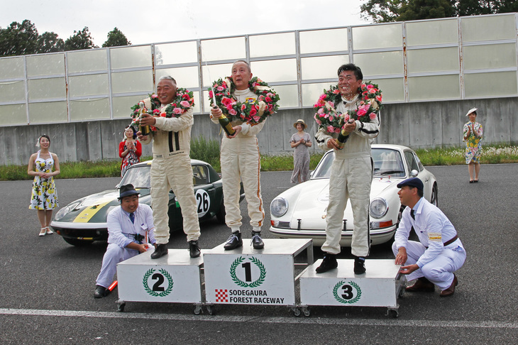 各レース終了後にはコース上で暫定表彰が行われ、ドライバーにはグリッドガールの祝福とシャンパンファイトが贈られる。これはエバーグリーン・カップで、左から2位の関口さん、優勝した生沢さん、そして1965年「ロータス・エラン」で3位に入った田中宏昌さん。