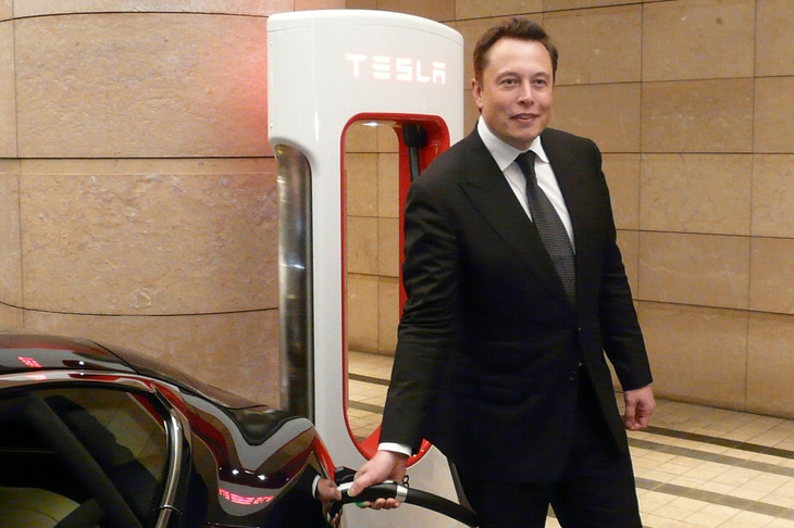 2014年の「モデルS」の納車開始セレモニーより、スーパーチャージャーによる充電のデモンストレーションを行うイーロン・マスク氏。　