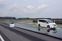 タイヤの溝の存在がどれほどウエット路面での制動力に影響があるのかを、「日産セレナ」を使って実証。左手に掲げられた看板の場所が、溝のあるタイヤの車両が止まった場所。溝のない白い車両は止まるまでの距離が10mほど長かった。