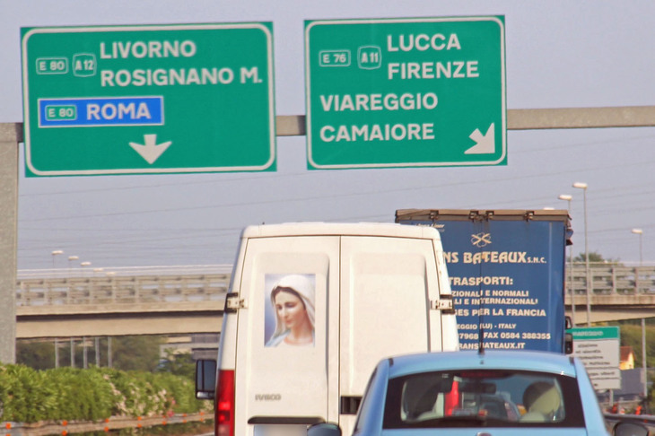 （写真H）。聖母マリアが描かれたバン。すぐ後方を走る水色の「フィアット500」には、いかにもご加護がありそうだ。