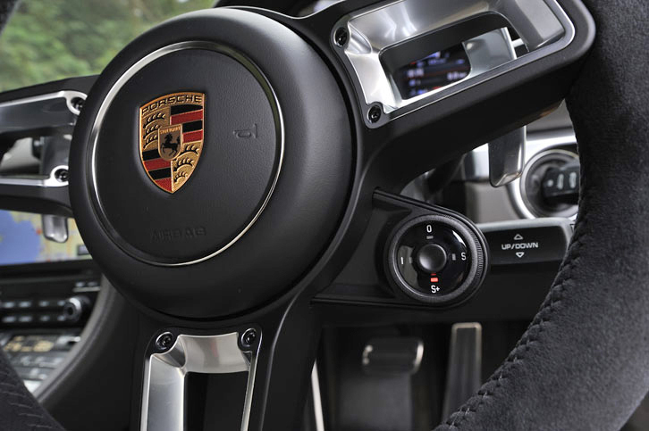 盾形のエンブレムが輝くステアリングホイール。そのセンター右下には、ダイヤル式の「プログラムスイッチ」を装備。好みの走行モードが選択できる。