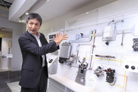 デンソー本社の技術展示スペースにて、コモンレールシステムの機構を説明するデンソーの竹内克彦氏。この機構を世界で初めて量産化したのも、実はデンソーなのだ。
    