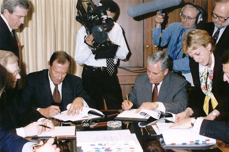 合併の誓約書にサインする、ダイムラー・ベンツのユルゲン・シュレンプ会長（左）と、クライスラーのロバート・イートン会長（右）。
