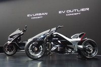 新「Hマーク」の適用拡大を含め、ホンダは2025年よりロゴ／エンブレムの意匠変更、採用変更を推進している。例えば二輪車では、電動モデルに四輪電動車と同じ「Honda」ロゴを採用すると発表した。写真は「ジャパンモビリティショー2025」に出展された「EVアーバンコンセプト」（写真左奥）と「EVアウトライアーコンセプト」（同右手前）。車体に描かれたロゴに注目。